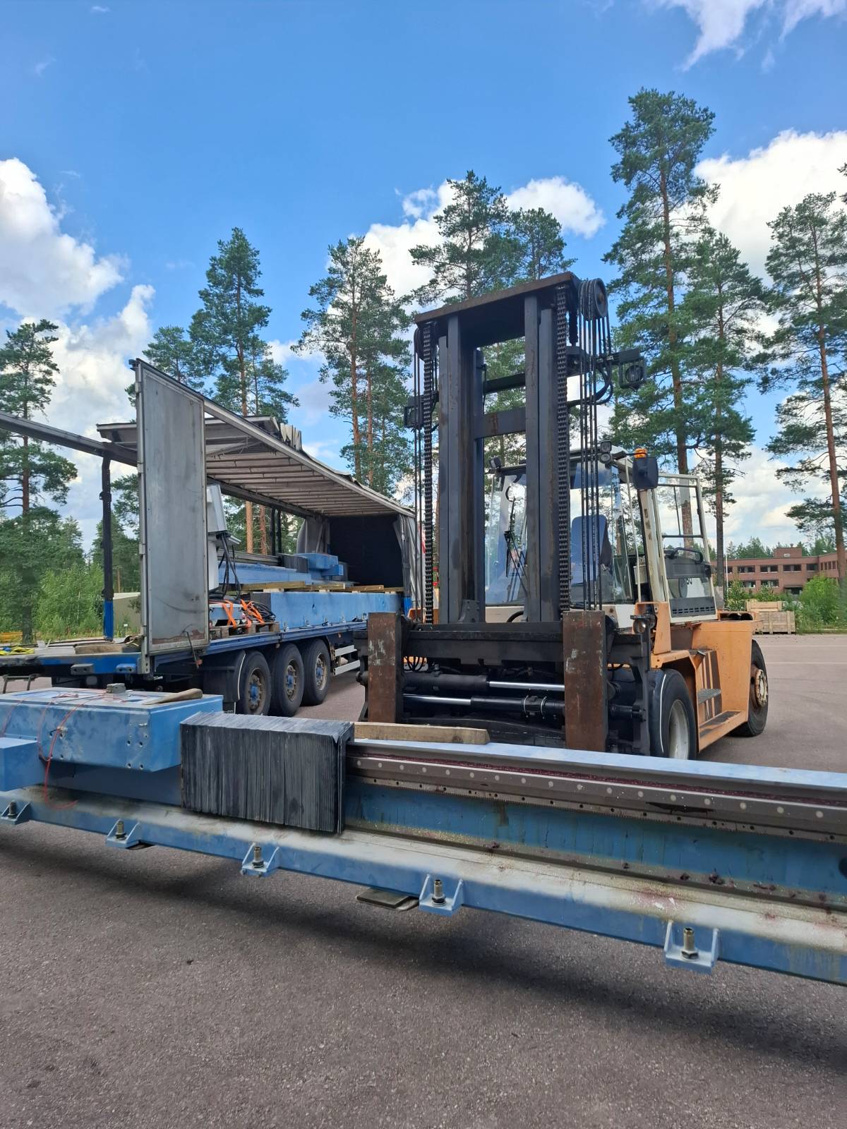 Trukki käsittelee pitkää raskasta komponenttia pihalla